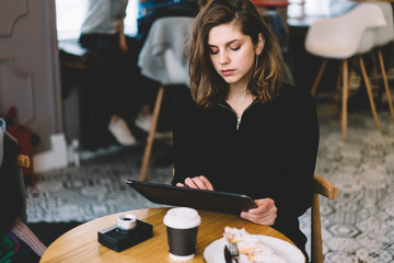 Adult pretty female surfing tablet at cafe