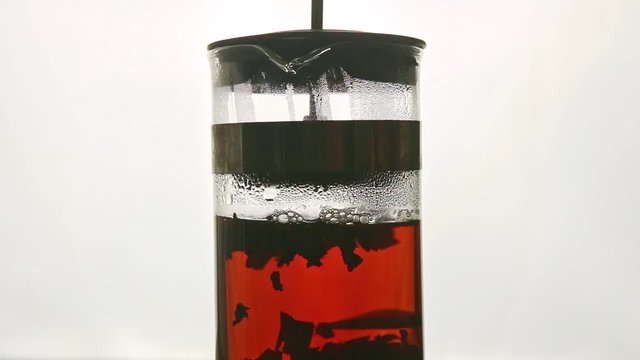 closeup hot tea stir in tall glass teapot spinning around against white
