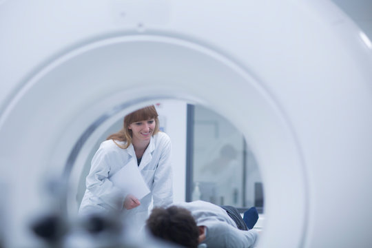 Patient in hospital during CT examination, female radiologist smiling
