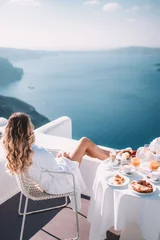 Tuinposter Young woman with blonde hair having breakfast in santorini greece © Mathilda
