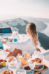 Young woman with blonde hair having breakfast in santorini greece