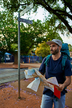 Backpacker standing on a street holding a map