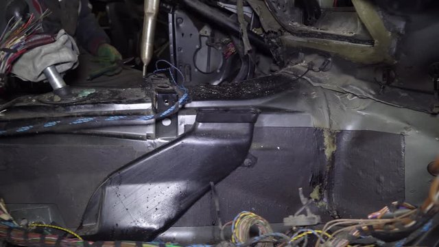 auto mechanic parses a car in a garage. He cuts the wire with scissors. Car on auto parts.