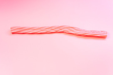 Elongated pink candy isolated on a flat colored background.