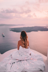 Young woman wrapped in sheets with blonde hair in santorini greece