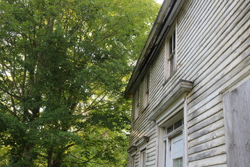 Old abandoned historic farmhouse with broken windows and peeling paint