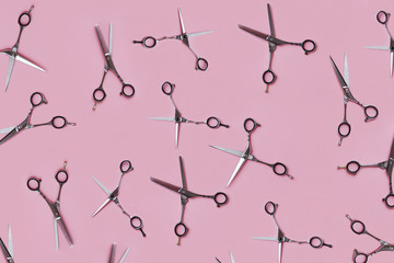 Three pairs of metal hairdresser scissors placed in an equally open position over pink background. Here are all-purpose shears and blending shears. Top view.