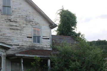 Old abandoned historic farmhouse with broken windows and peeling paint