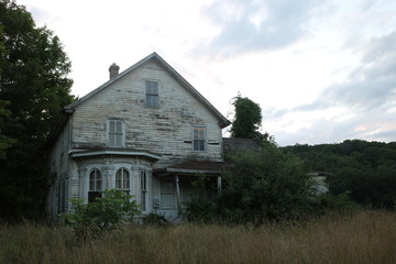 Fototapeta na wymiar Old abandoned historic farmhouse with broken windows and peeling paint