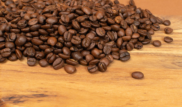 Dark brown whole coffee beans on wood background with copyspace