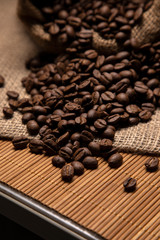 Roasted coffee beans spill out of the tow bag. Coffee close-up.