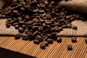 Appetizing roasted coffee beans on burlap, close-up.