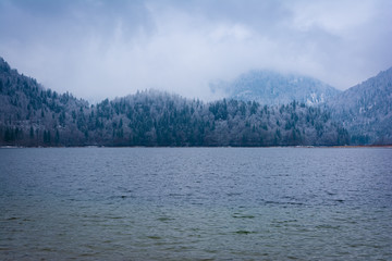 Berge am See mit Wolken und Schnee