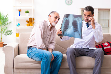 Obraz premium Young male doctor visiting old patient at home