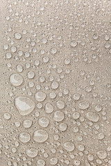 Texture of water drops on fabric textile close-up. Rain background in beige color. Waterproof surface abstract. 
