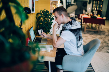 Freelance young man using laptop sitting in workspace at home