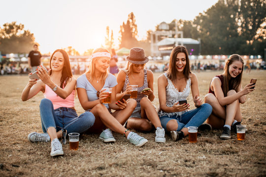 Friends drinking beer and using phones at music festival