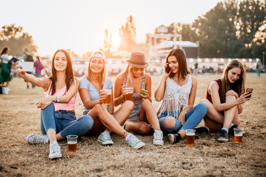 Friends drinking beer and using phones at music festival