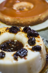 Brazilian manjar branco blancmange with dried plums with milk pudding on the background