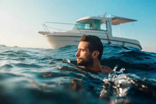 Young Man Swimming In The Sea Infront Of Yacht