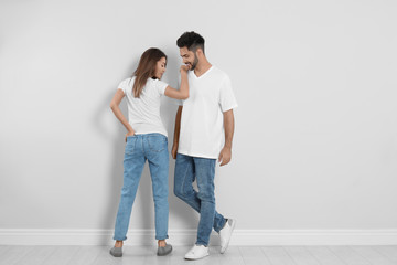 Fototapeta na wymiar Young couple in stylish jeans near light wall