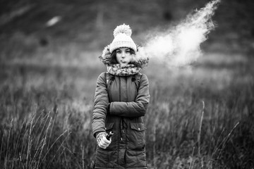 Vaping teenager. Young beautiful white teeage girl in casual clothes smokes an electronic cigarette...