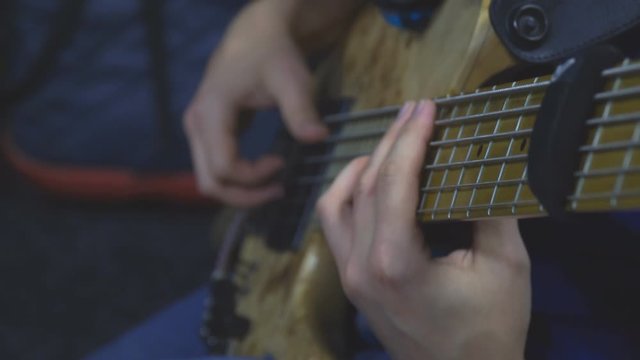 The bass player plays on a five-string bass guitar close-up. Plays bass guitar. Selective focus