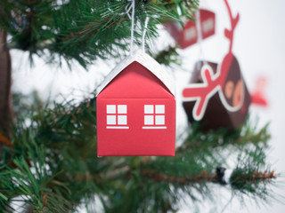 Red paper house with Windows hanging on Christmas tree. Concept of new housing, mortgages, property purchases, Christmas and new year