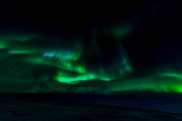 Aurora borealis in night northern sky. Ionization of air particles in the upper atmosphere.