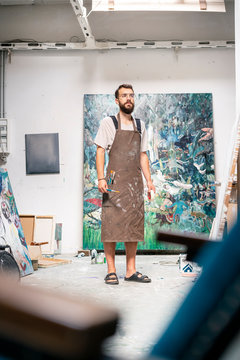 Artist standing in his studio, holding paint brush