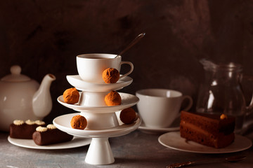 White saucer pyramid with cup of tea on top decorated with chocolate truffles on surved dessert table on dark background. Creative concept, restaurant, candy shop. Horizontal for wallpaper, postcard