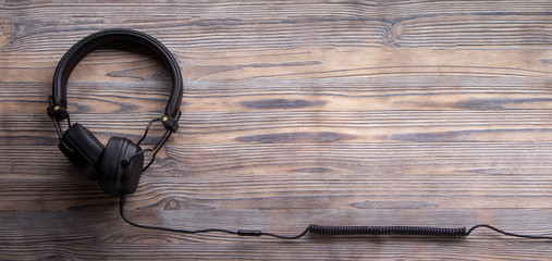 Modern Headphones with long cable on wood background, Music online concept, top view, mockup