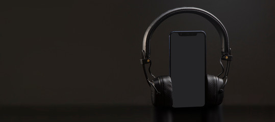 black headphones on smartphone music online concept, mockup