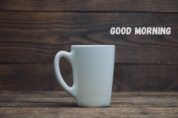 A white cup stands on a wooden table. Tea and coffee in the morning
