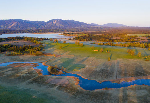 Germany, Bavaria, Uffing am Staffelsee, Aerial view of river Ach with Staffelsee lake and mountains in background