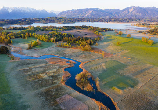 Germany, Bavaria, Uffing am Staffelsee, Aerial view of river Ach with Staffelsee lake and mountains in background