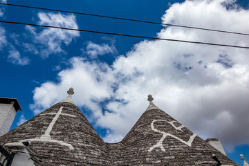 Fototapeta na wymiar Roofs of truli, typical whitewashed cylindrical houses in Alberobello, Puglia, Italy with amazing blue sky with clouds and Sun shining