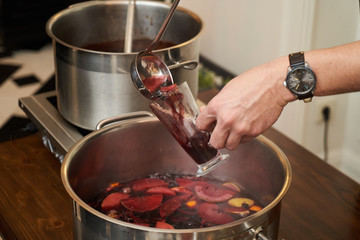 Man pours fruit compote into a glass, close-up. Healthy compote