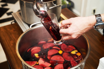 Man pours fruit compote into a glass, close-up. Healthy compote