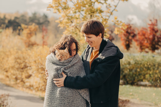 Young couple with a red cat on a background of an autumn park.