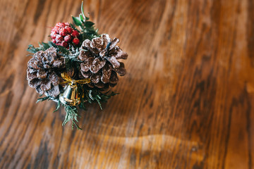 Christmas Background with snowy pine core and golden/yellow bell on brown / wooden background. Happy New Year Celebration background (with selective focus)
