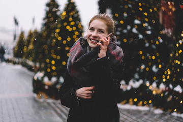 Attractive woman standing in front of Christmas trees and talking on phone