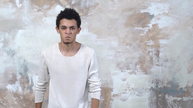 Young man alone isolated on painted wall looking camera angry