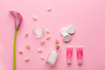 Skin care concept. Sea salt, soap, micellar water and calla lily flower on a pink pastel background