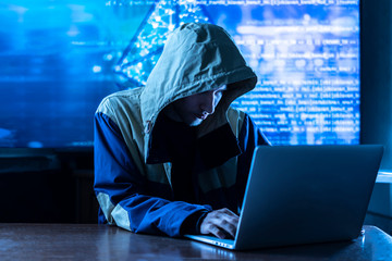 anonymous hacker braking the personal online data in his office, dark blue, deep web