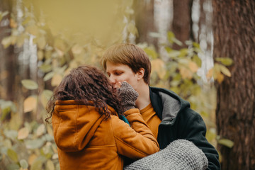 Young man and woman kiss in the autumn forest.