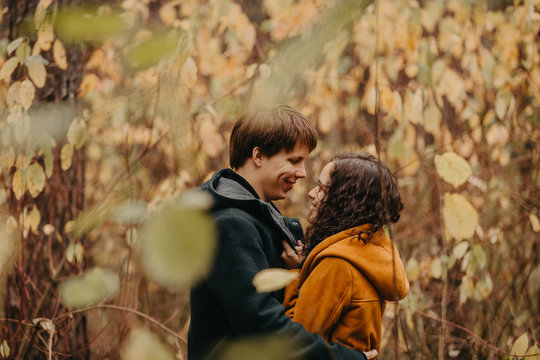 Young man and woman kiss in the autumn forest.
