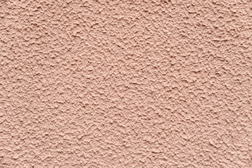 Beige chipped textured paint with sand on the wall.