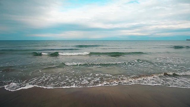 Footage of waves hitting the sand on an empty beach, by the sea.