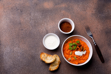 Pumpkin dish with toasted baguette slices, spices and sour cream on a brown background.
